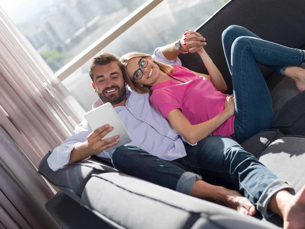 Pareja Joven Relajándose Casa Usando Tabletas Leyendo Sala Estar Sofá — Foto de Stock