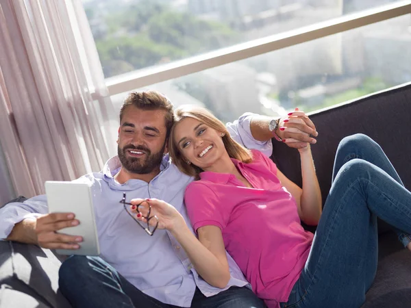 Pareja Joven Relajándose Casa Usando Tabletas Leyendo Sala Estar Sofá —  Fotos de Stock