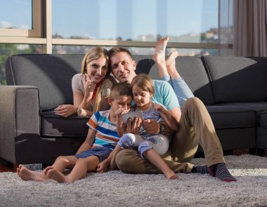 Mutlu Genç Aile, kanepede oturup tabletle birlikte oynuyor.