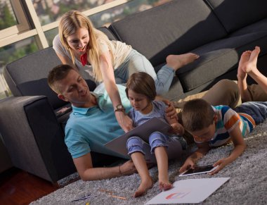 Mutlu genç aile oynarken birlikte evde bir tablet ve bir çocuk çizim kümesi kullanma