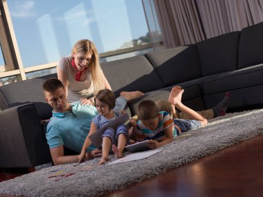 Mutlu genç aile oynarken birlikte evde bir tablet ve bir çocuk çizim kümesi kullanma