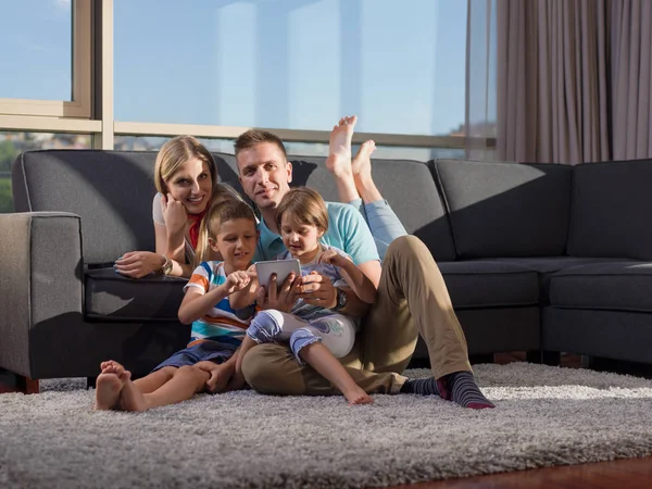 幸せな若い家族はソファに座って自宅でタブレットと一緒に遊ぶ — ストック写真