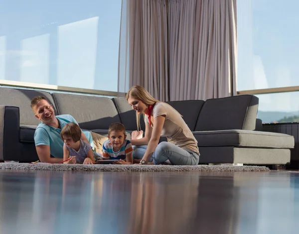 快乐的年轻家庭一起玩平板电脑在家里坐在地板上 — 图库照片