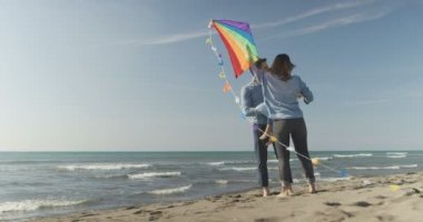 Çocukların dinlendiği ve sonbahar günü kumsalda eğlendiği bir aile.