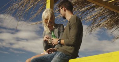 Kumsalda bira içen çift.