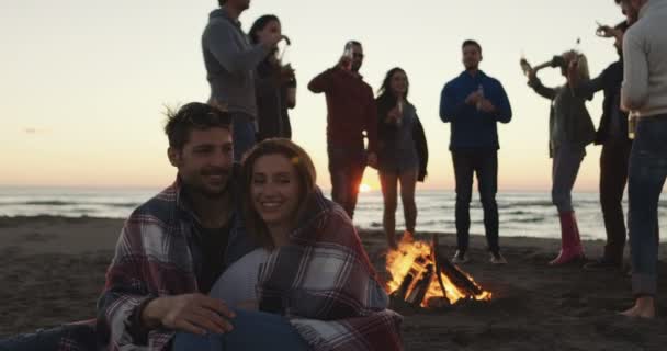 夕日のビーチでたき火を囲んで踊る友達のグループ — ストック動画