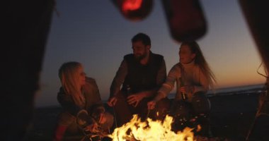 Dostlar kumsalda şenlik ateşiyle eğleniyor.
