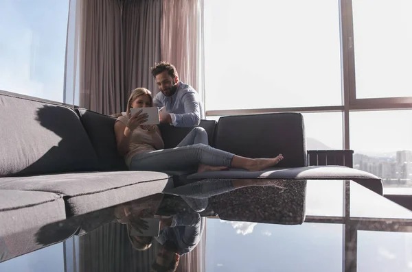 Пара розслабляється вдома за допомогою планшетного комп'ютера — стокове фото