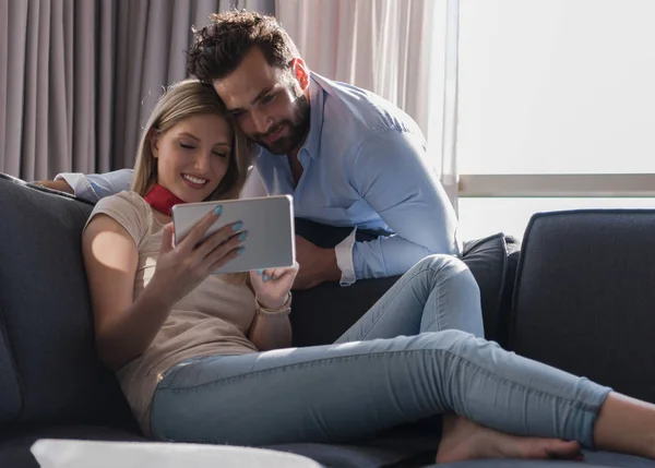 Пара розслабляється вдома за допомогою планшетного комп'ютера — стокове фото