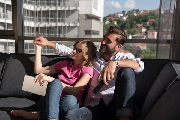 Jovem casal sentado no sofá — Fotografia de Stock