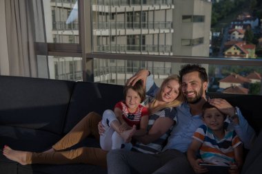 Mutlu çift çocuklarla evde kanepede tablet bilgisayar kullanarak vakit geçiriyor.