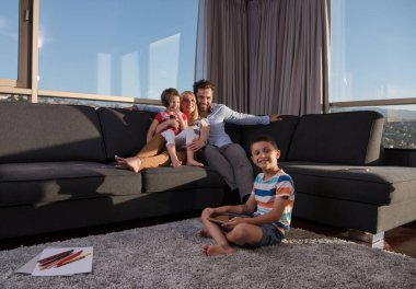 Mutlu çift çocuklarla evde kanepede tablet bilgisayar kullanarak vakit geçiriyor.