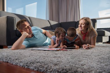 Mutlu Genç Aile, tablet ve çizim setiyle evde birlikte oynuyor.