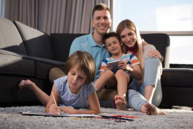 Mutlu Genç Aile, tablet ve çizim setiyle evde birlikte oynuyor.