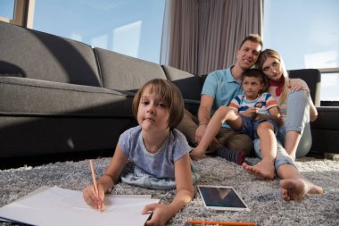 Mutlu Genç Aile, tablet ve çizim setiyle evde birlikte oynuyor.