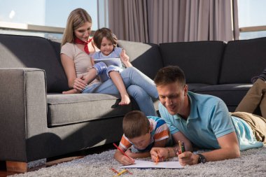 Mutlu Genç Aile, tablet ve çizim setiyle evde birlikte oynuyor.