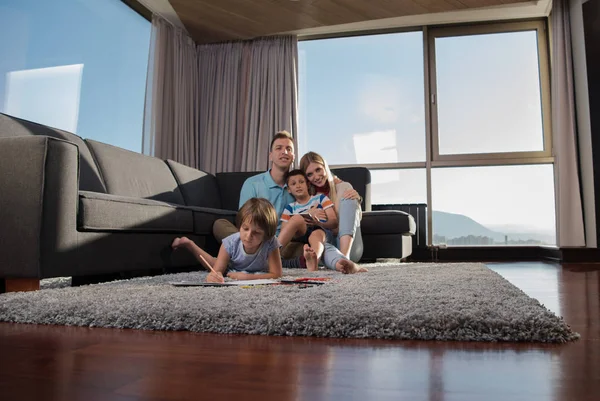 幸せな若い家族がタブレットと子供の絵セットを使って床の上で一緒に遊んでいます — ストック写真
