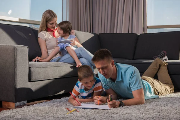 快乐的年轻家庭在家里用平板电脑和儿童绘图集一起在地板上玩耍 — 图库照片