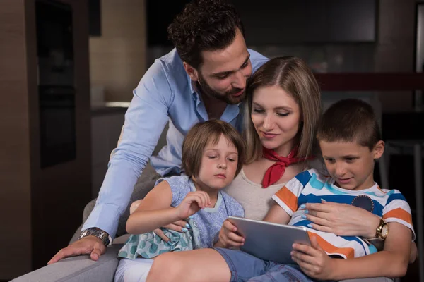 幸せなカップルは自宅のアームチェアでタブレットを使って子供たちと時間を過ごし — ストック写真