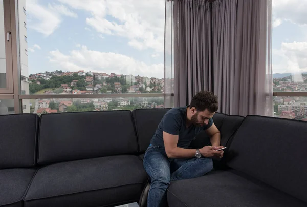 Молодий випадковий чоловік використовує мобільний телефон вдома — стокове фото