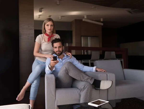 年轻夫妇在沙发上看电视一起在他们的豪宅 — 图库照片
