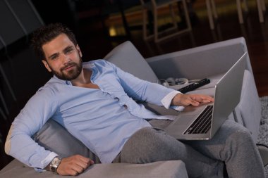 Teknoloji, ev ve yaşam tarzı kavramı insanın evde dizüstü bilgisayar kullanarak ve kanepede oturarak çalışması.