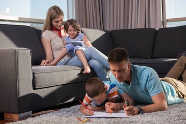 Mutlu Genç Aile, tablet ve çizim setiyle evde birlikte oynuyor.