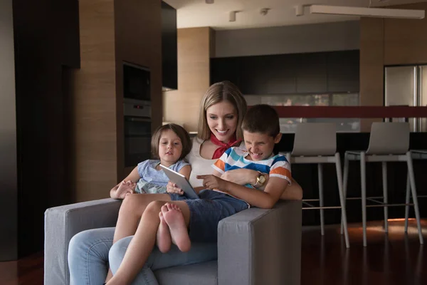 快乐的妈妈在家里的扶手椅上和孩子们一起使用平板电脑 — 图库照片