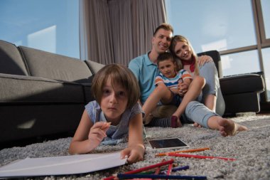 Mutlu Genç Aile, tablet ve çizim setiyle evde birlikte oynuyor.