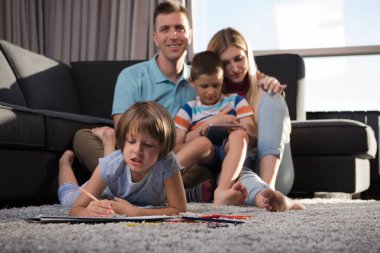 Mutlu Genç Aile, tablet ve çizim setiyle evde birlikte oynuyor.