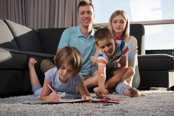 快乐的年轻家庭在家里用平板电脑和儿童绘图集一起在地板上玩耍 — 图库照片