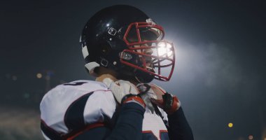 Amerikan Futbol oyuncu koyarak üzerinde kask ile büyük stadyum