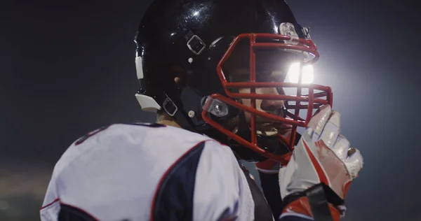 Американский Футболист Надевает Защитный Шлем Против Ярких Огней Освещения Стадиона — стоковое фото