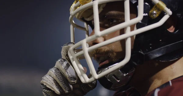 美国足球运动员戴上防护头盔 挡住明亮的体育馆照明灯 — 图库照片