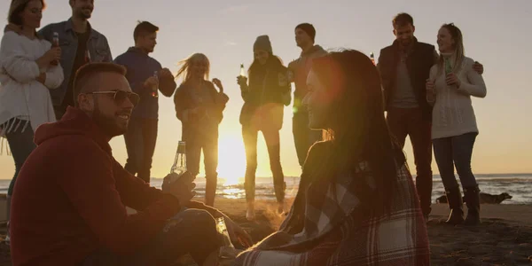 快乐无忧无虑的年轻朋友们 在太阳即将落山的时候 一边在海滩边尽情享受着欢乐 一边喝啤酒 — 图库照片