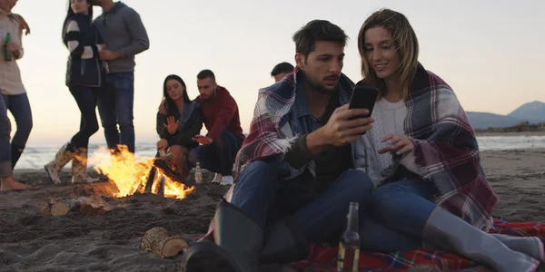 Pár Pomocí Mobilu Během Plážové Párty Přáteli Pití Piva Baví — Stock fotografie