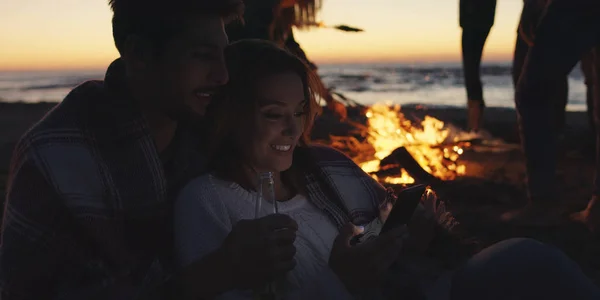 Paar Met Behulp Van Mobiele Telefoon Tijdens Strandfeest Met Vrienden — Stockfoto