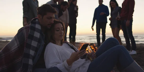 Paar Met Behulp Van Mobiele Telefoon Tijdens Strandfeest Met Vrienden — Stockfoto