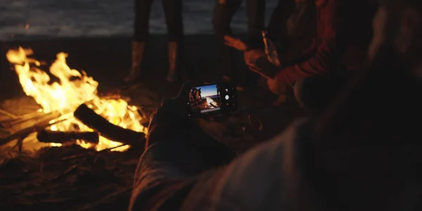 Boy Shows Girl Picture His Phone Campfire Beach — Stock fotografie