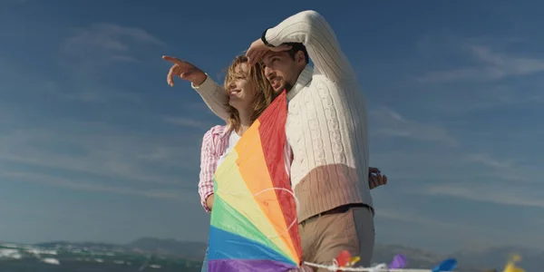 Happy couple having fun with kite on beach — Stock Photo, Image