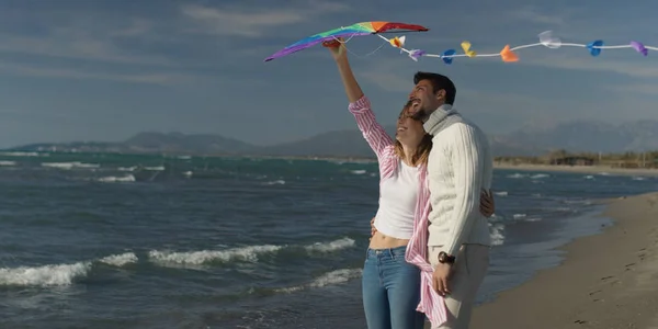 Happy couple having fun with kite on beach — Stock Photo, Image