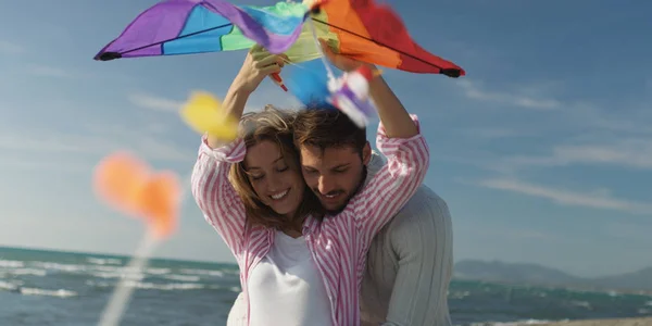Casal feliz se divertindo com pipa na praia — Fotografia de Stock