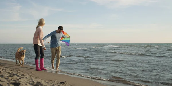 Couple with dog having fun on beach on autmun day — Stock Photo, Image