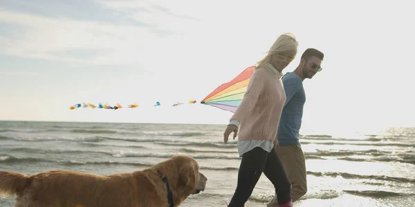 Par med hund ha kul på stranden på autmun dag — Stockfoto