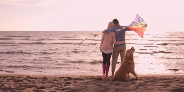 couple with dog having fun on beach on autmun day clipart