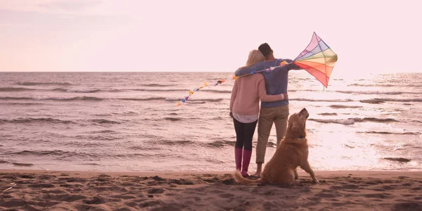 Couple with dog having fun on beach on autmun day — Stock Photo, Image