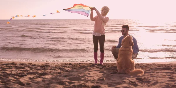 Pareja con perro divirtiéndose en la playa en día autmun —  Fotos de Stock