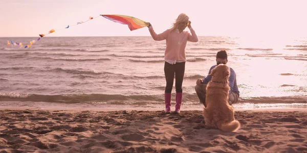 Para z psem zabawy na plaży na autmun dzień — Zdjęcie stockowe