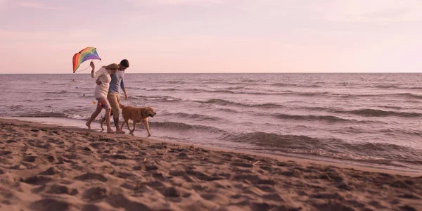 Pareja con perro divirtiéndose en la playa en día autmun —  Fotos de Stock