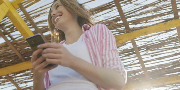 Teléfono inteligente mujer mensajes de texto en el teléfono celular en la playa —  Fotos de Stock